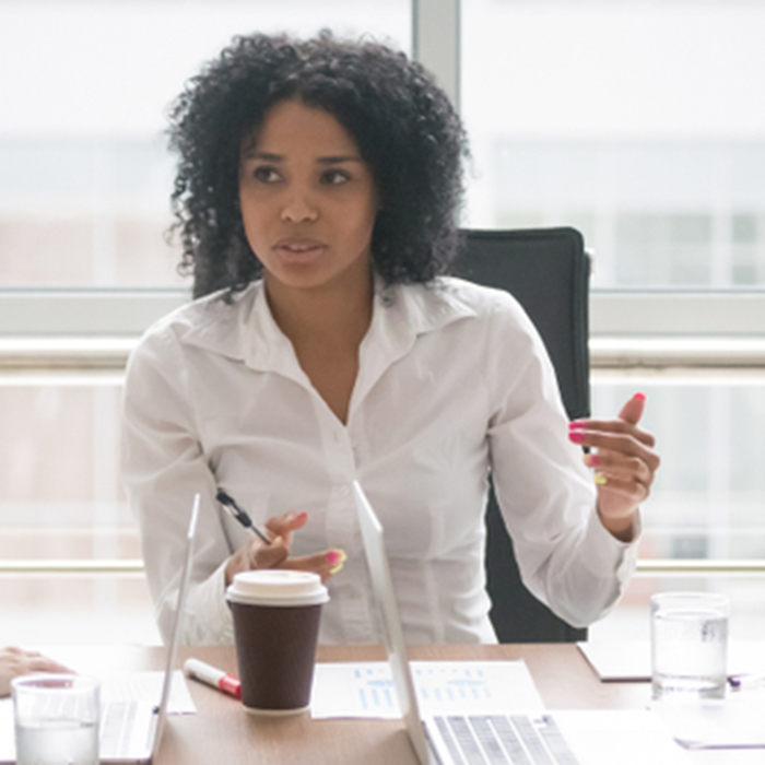 Executive lady in a white shirt seated at a table meeting - Our work in Leadership and consulting