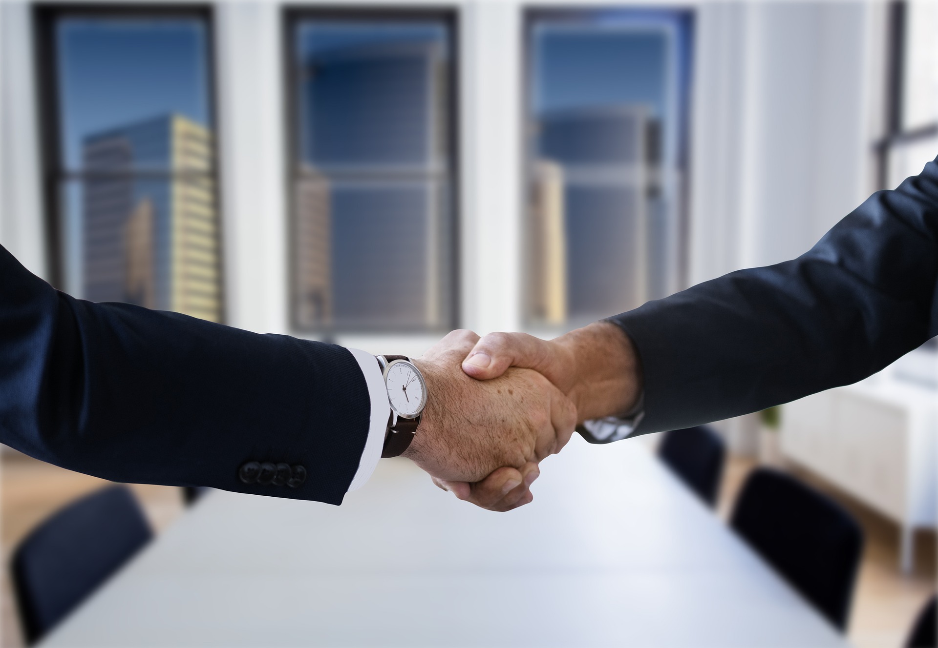 Business men shaking hands in front of a boardroom table in Executive Search Firm