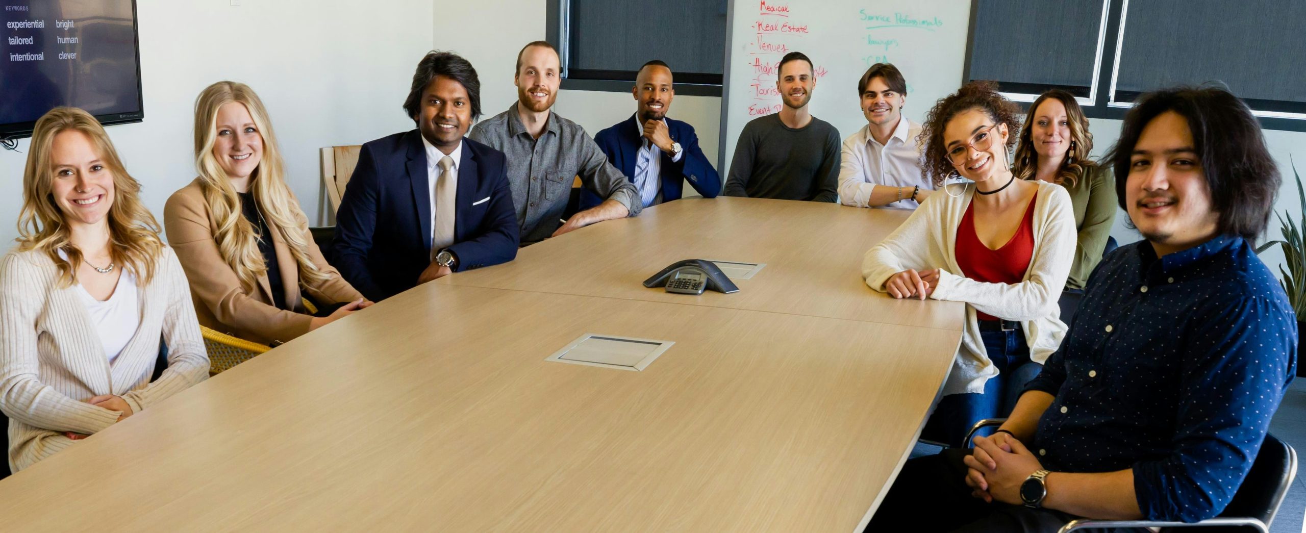 Group of diverse professionals smiling and sitting around a conference table in a modern office setting