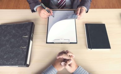 Close up of a recruiter and candidate sitting across from each other with a desk and between them